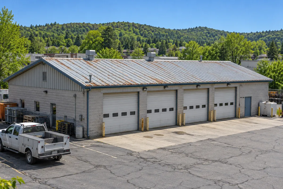 Metal service building with four overhead doors and a weathered panel roof